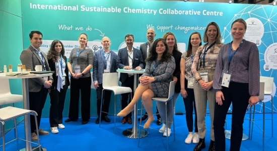 several people standing in a fair booth smiling into camera