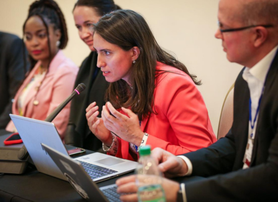 women in red blazer speaking in a table microphone